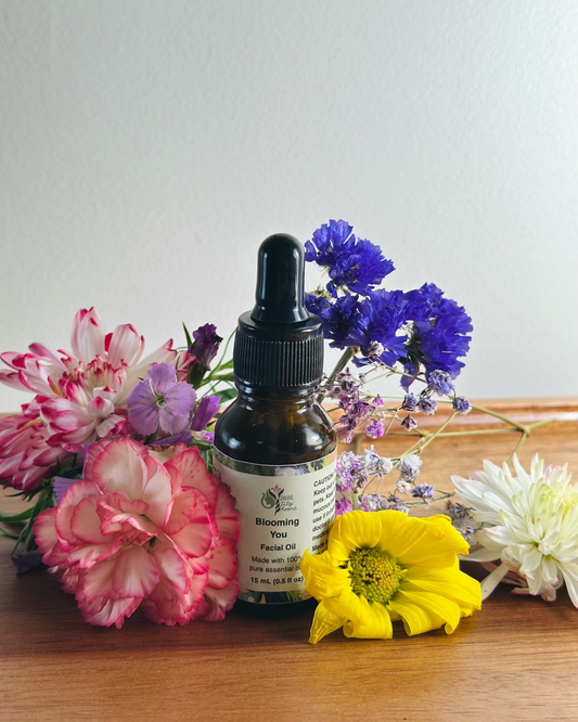 Facial oil dropper bottle with colorful flowers on a wooden surface