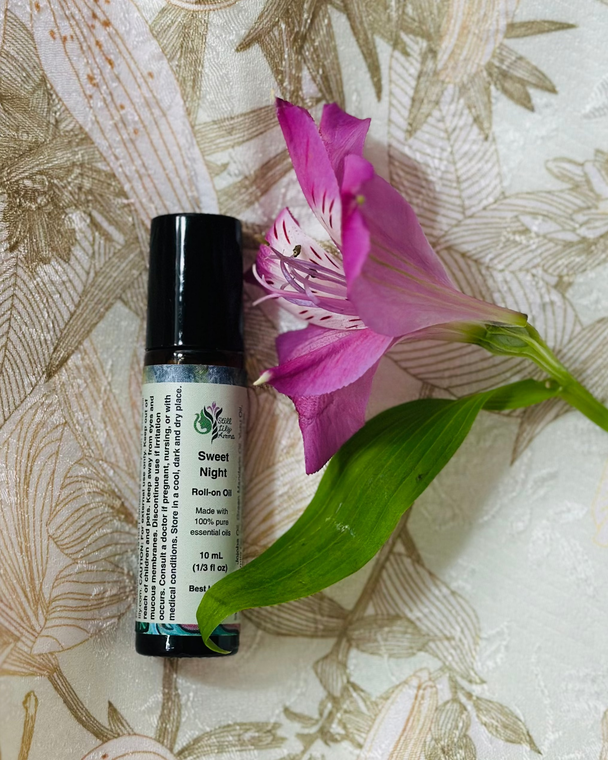 Roll-on bottle labeled 'Sweet Night' with a pink flower on a floral-patterned fabric background