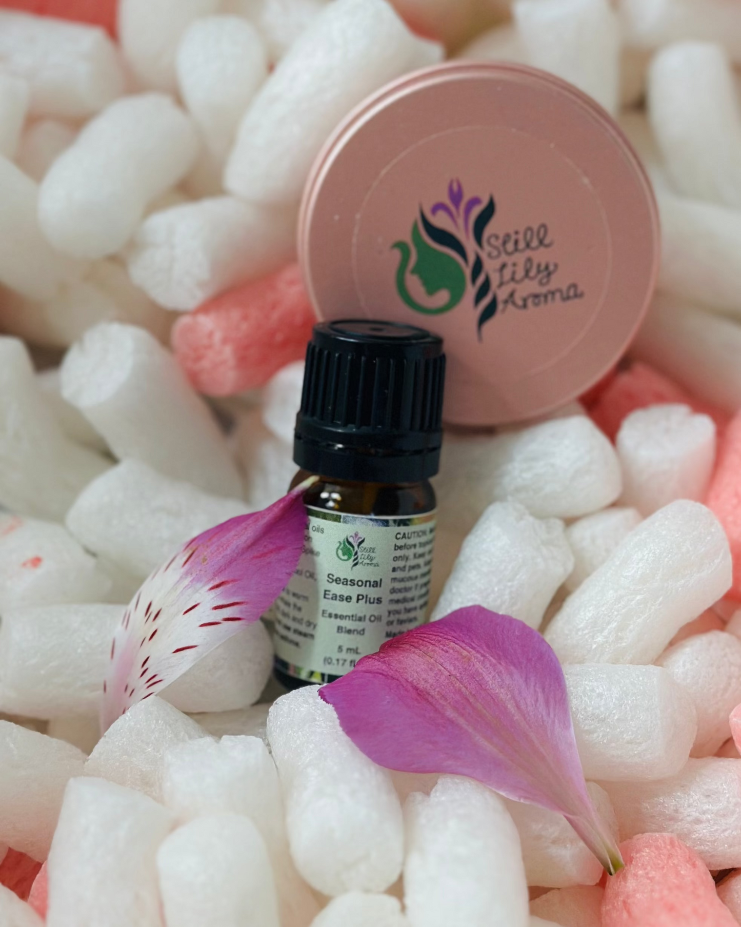 Small bottle of Seasonal Ease Plus essential oil on a bed of white packing peanuts.